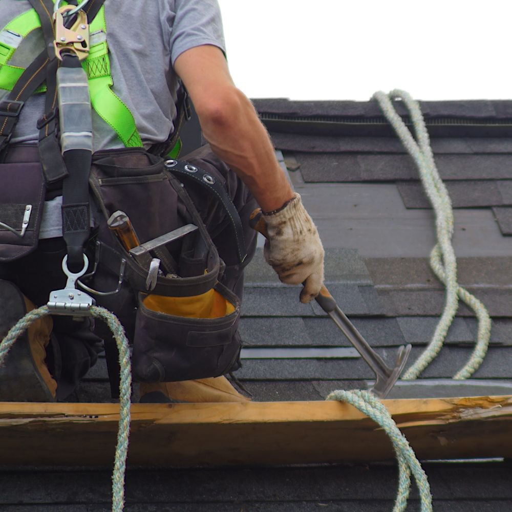Roofer in safety gear restoring a tiled roof